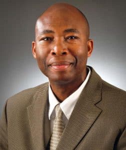 a man wearing a suit and tie smiling at the camera