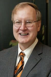 a man wearing a suit and tie smiling at the camera