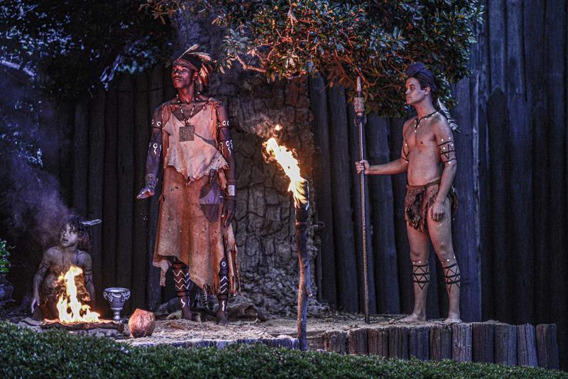 a man and a woman standing in front of a fire