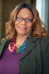 a woman wearing glasses and smiling at the camera