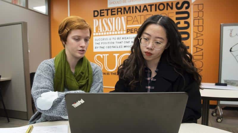 a woman sitting at a table in front of a laptop