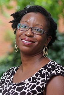 a woman wearing glasses and smiling at the camera