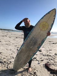 a man carrying a surf board on a beach