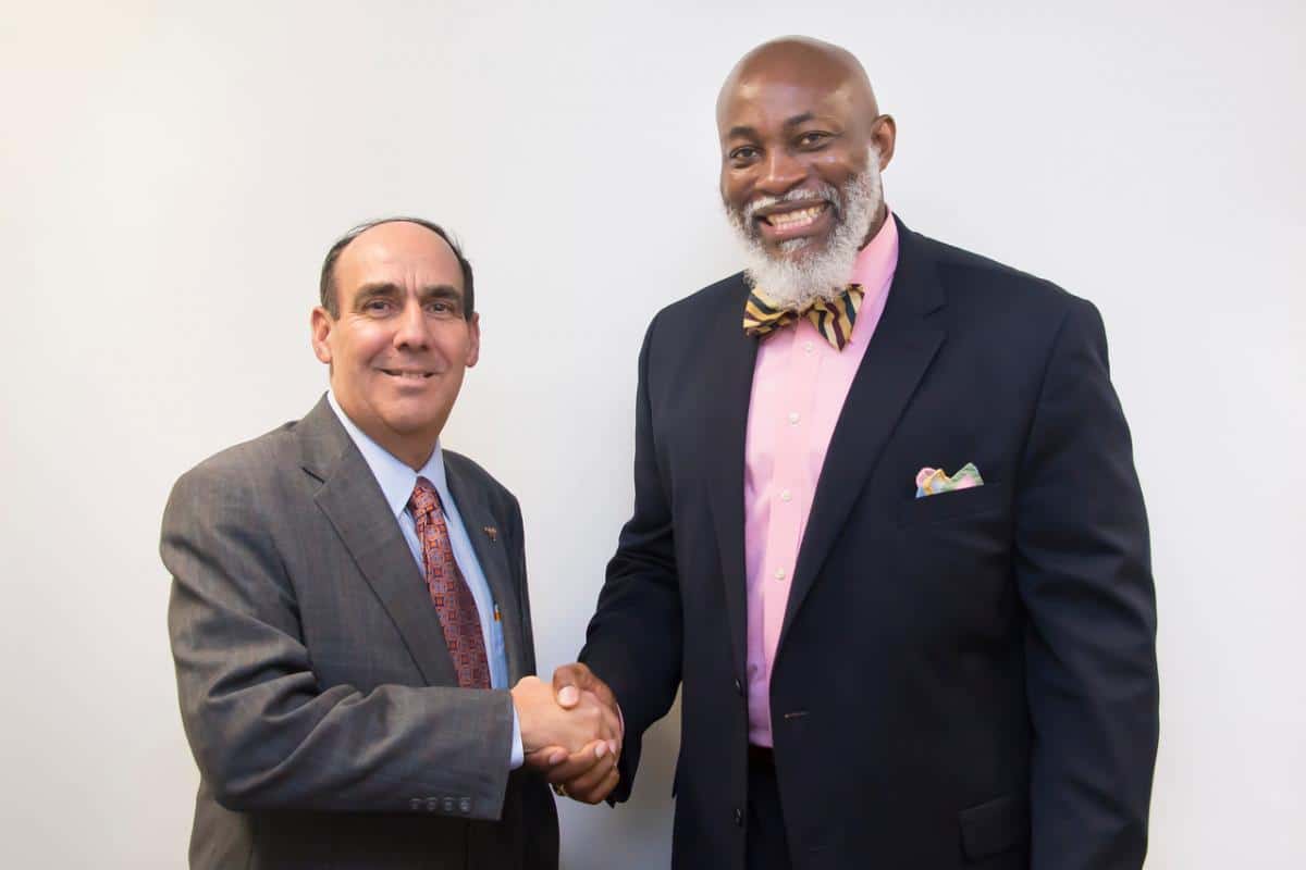 Dr. Carl A. Stockton and Dr. Lorenza Pharrams shaking hands.