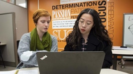 a person sitting at a table in front of a laptop