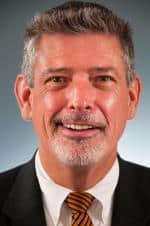 a man wearing a suit and tie smiling at the camera