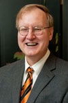 a man wearing a suit and tie smiling at the camera