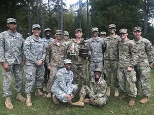 a group of people posing for a photo in front of a military uniform