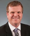 a man wearing a suit and tie smiling at the camera