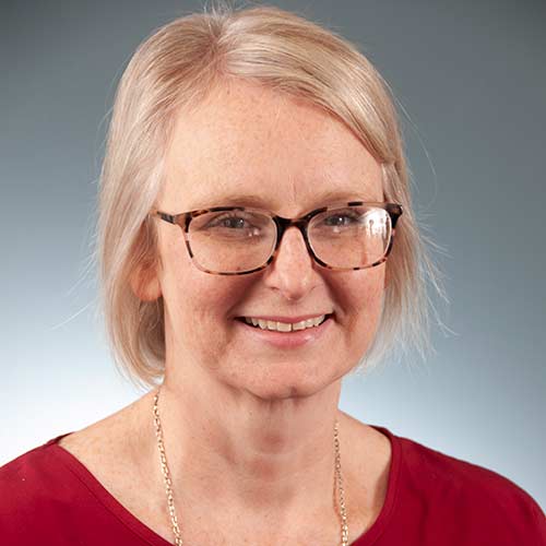 a woman wearing glasses and smiling at the camera