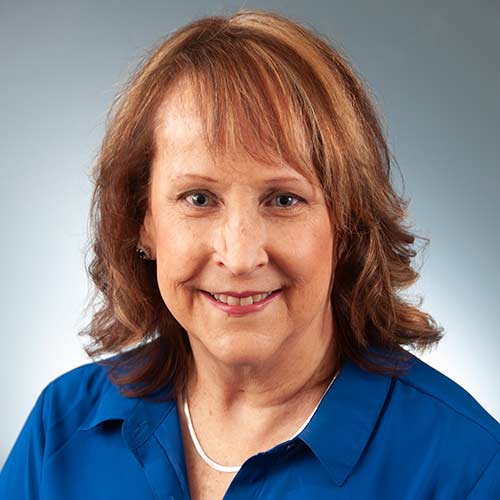 a woman in a blue shirt and smiling at the camera