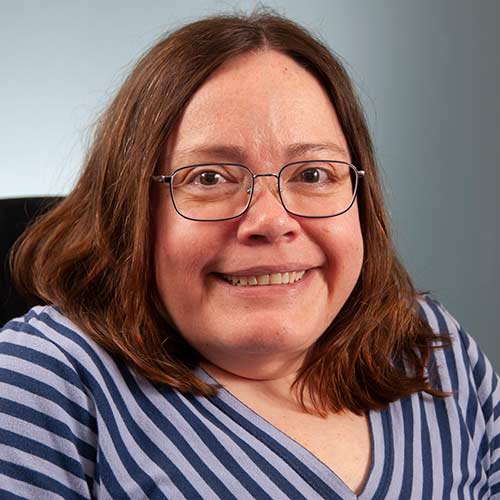 a woman wearing glasses and smiling at the camera