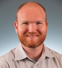 a man wearing glasses and smiling at the camera