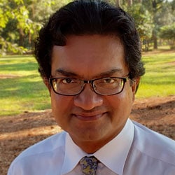 a man wearing glasses and smiling at the camera