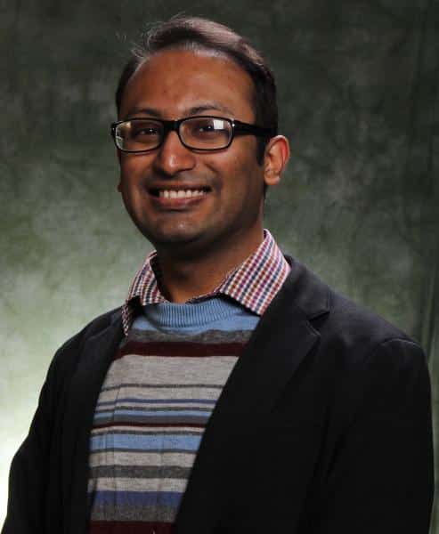 a man wearing glasses and smiling at the camera