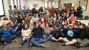 a group of people sitting in front of a crowd posing for the camera