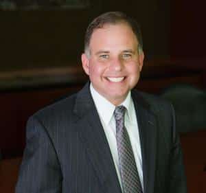 a man wearing a suit and tie smiling at the camera