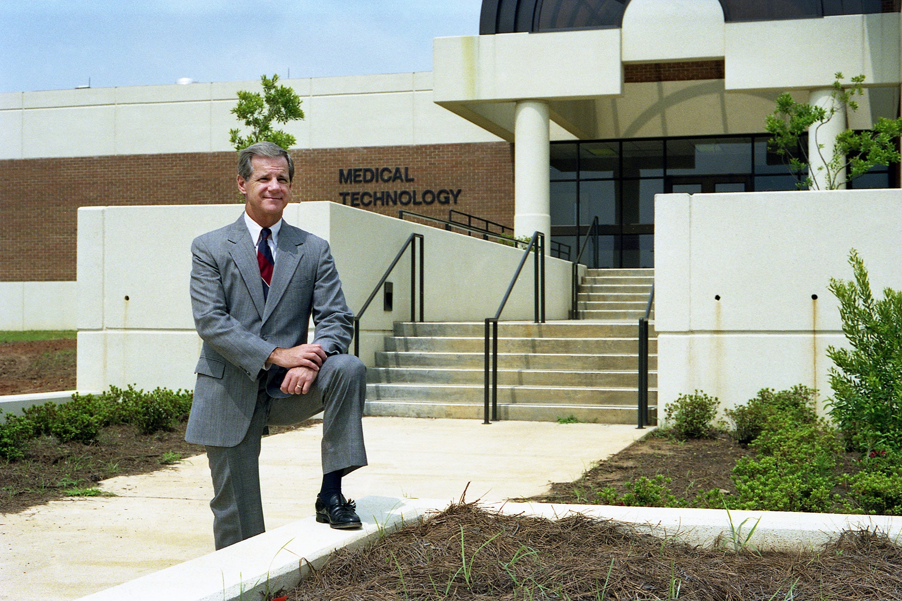 a man in a suit standing in front of a building