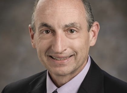 a man wearing a suit and tie smiling at the camera