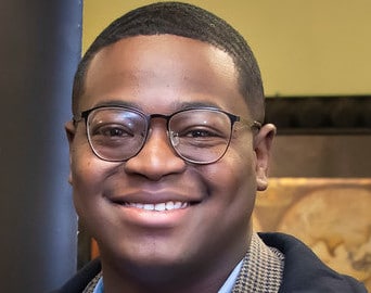 a man wearing glasses and smiling at the camera