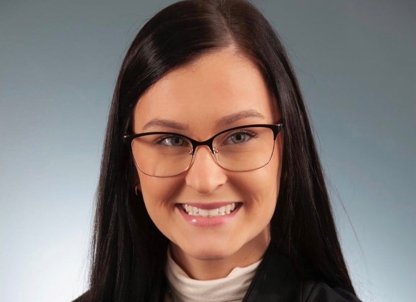 a woman wearing glasses and smiling at the camera