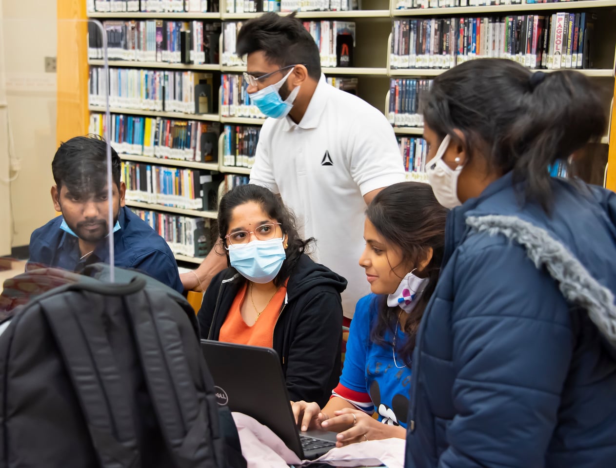 a group of people looking at a book shelf