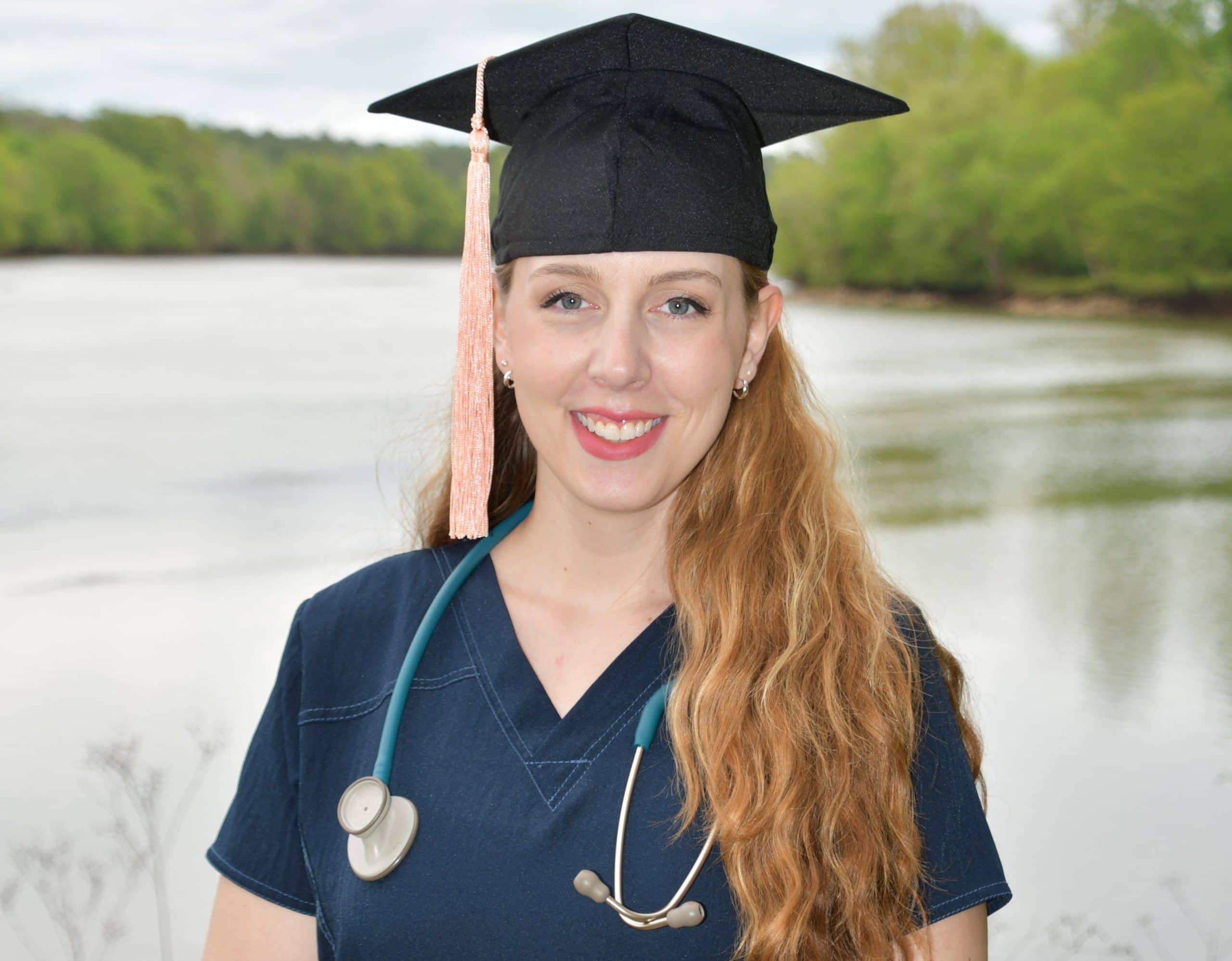 a woman wearing a hat standing in front of a body of water