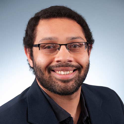 a man wearing glasses and smiling at the camera