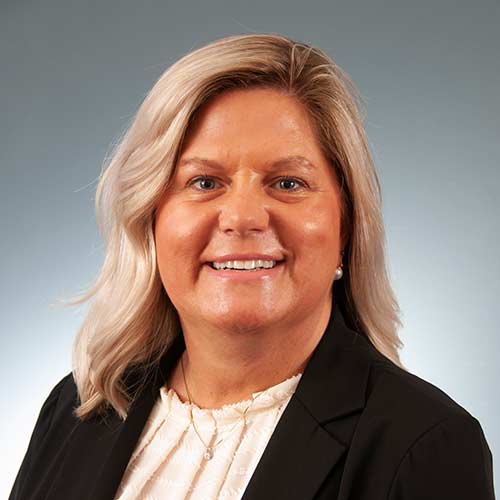 a woman wearing a suit and tie smiling at the camera