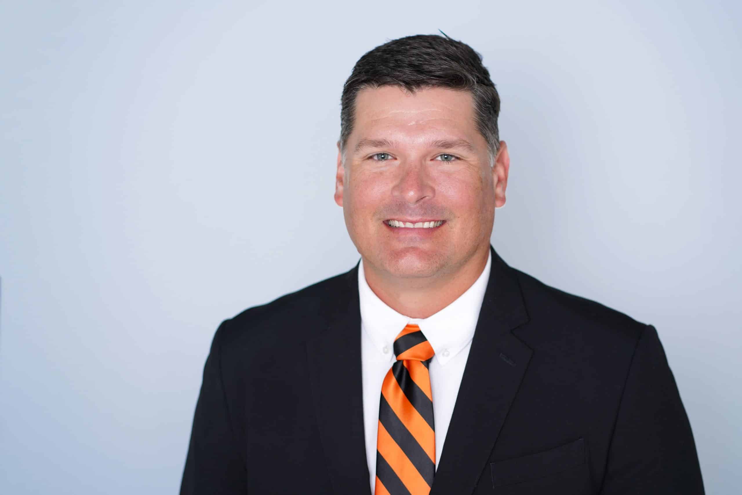 a man wearing a suit and tie smiling at the camera