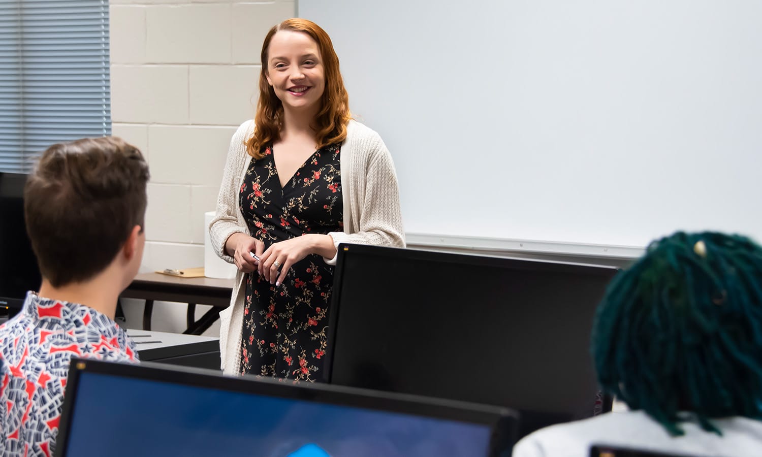 a woman standing in front of a laptop computer