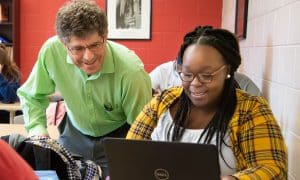 a man and a woman sitting at a table using a laptop