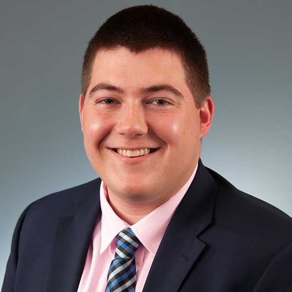a man wearing a suit and tie smiling at the camera
