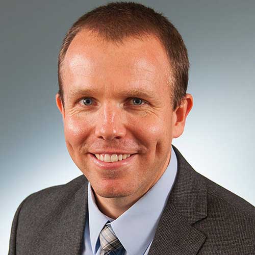 a man wearing a suit and tie smiling at the camera