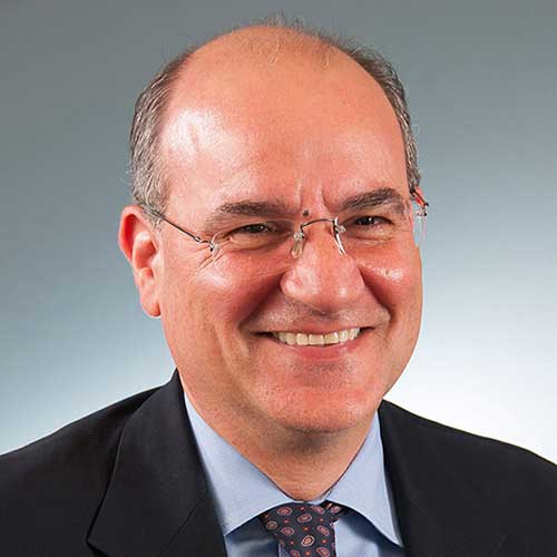 a man wearing a suit and tie smiling at the camera