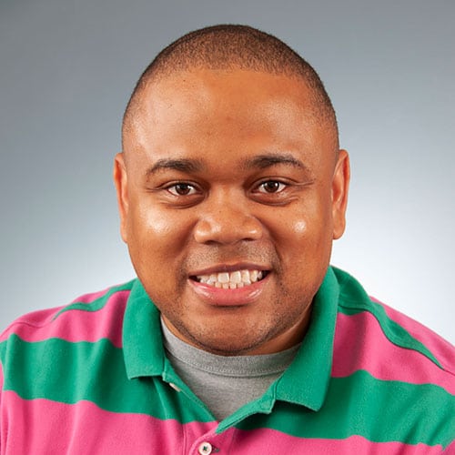 a man wearing a green shirt smiling for a photo