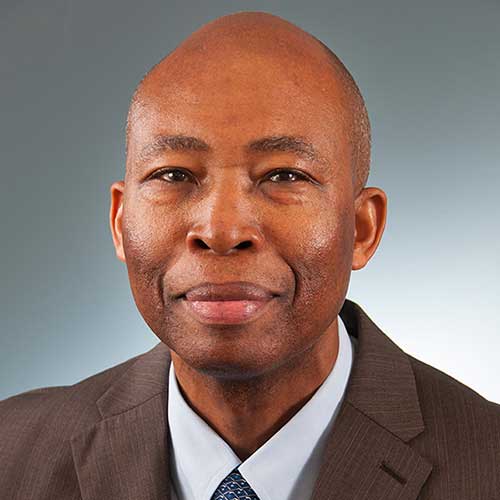 a man wearing a suit and tie smiling and looking at the camera