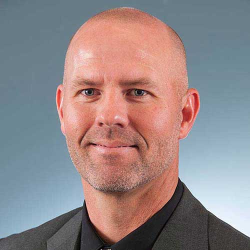 a man wearing a suit and tie smiling at the camera