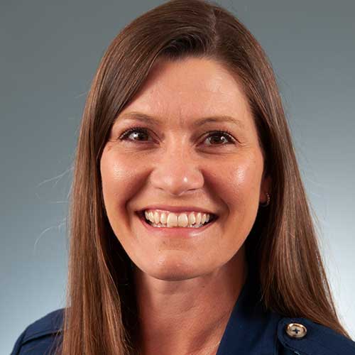a woman wearing glasses and smiling at the camera