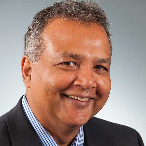 a man wearing a suit and tie smiling at the camera