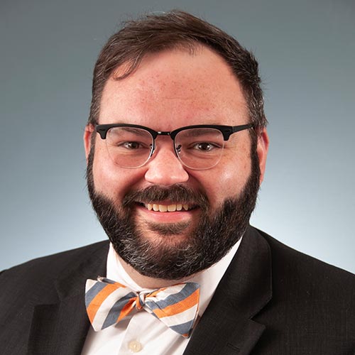 a man wearing a suit and tie smiling at the camera