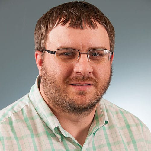 a man wearing glasses and smiling at the camera