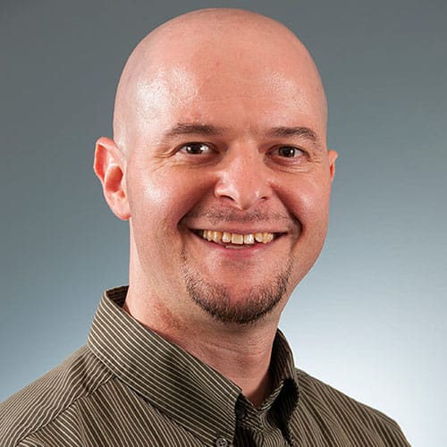 a man wearing a suit and tie smiling at the camera