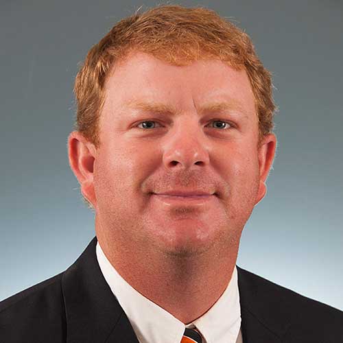 a man wearing a suit and tie smiling at the camera
