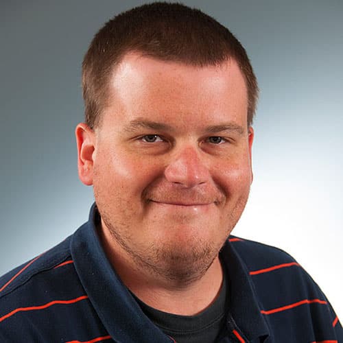 a man wearing glasses and smiling at the camera