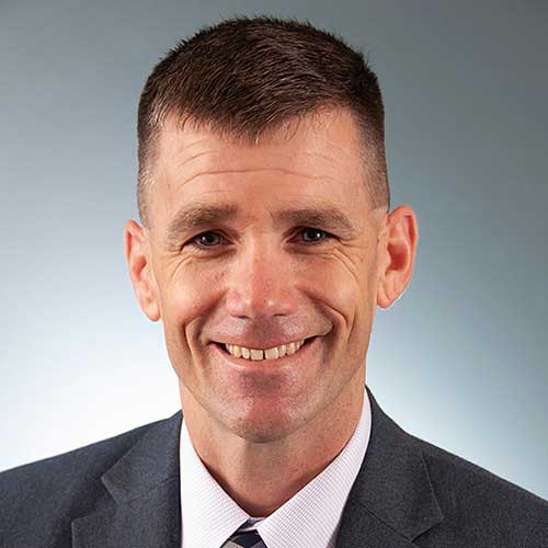 a man wearing a suit and tie smiling at the camera