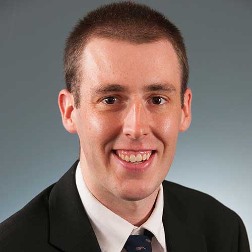 a man wearing a suit and tie smiling at the camera