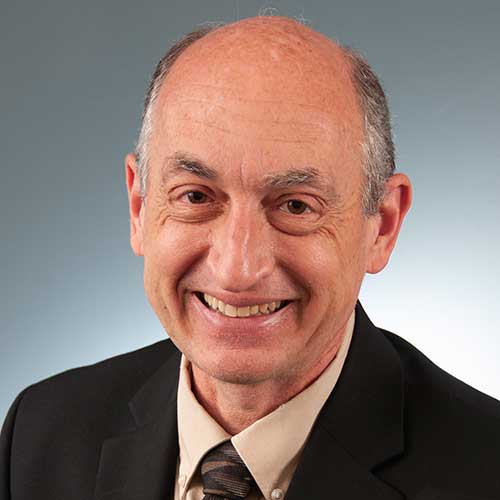 a man wearing a suit and tie smiling at the camera