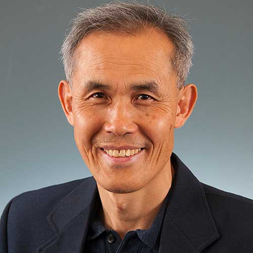 a man wearing a suit and tie smiling at the camera