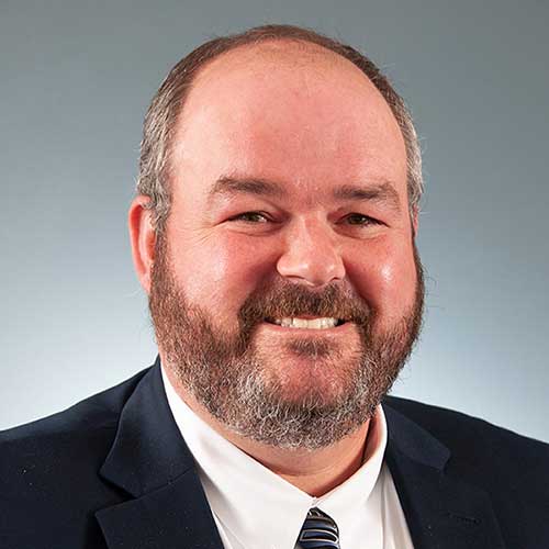 a man wearing a suit and tie smiling at the camera